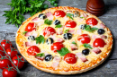 Pizza avec du bacon, des olives, et des tomates