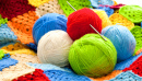 Des pelotes de laine et une couverture au crochet