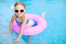 16521054-adorable-little-girl-with-inflatable-ring-at-swimming-pool