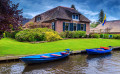 Maison pieds dans l’eau et bateaux à moteur amarrés, Giethoorn